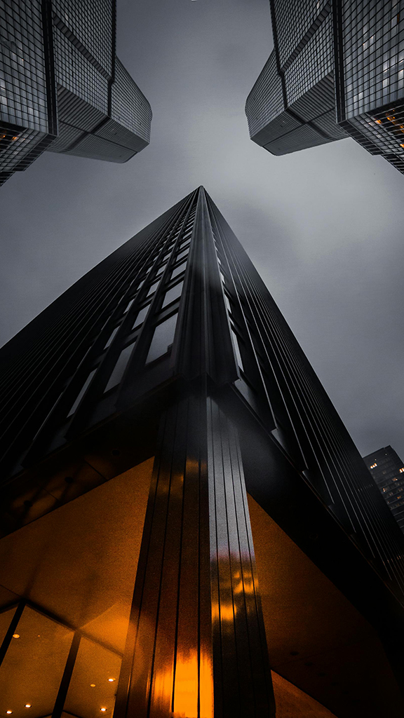 Dramatic low-angle view of modern city skyscrapers at dusk.